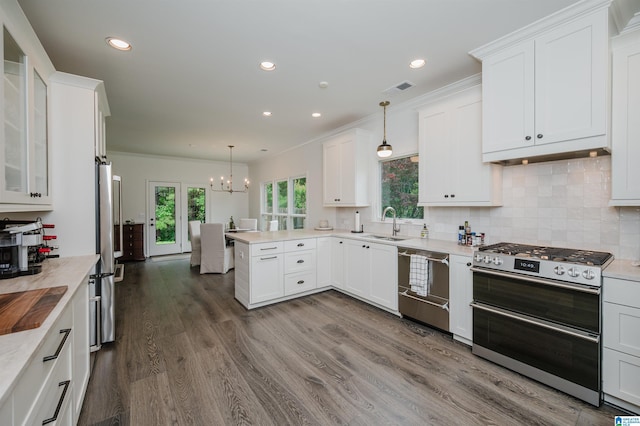 kitchen with stainless steel appliances, a chandelier, a peninsula, light countertops, and white cabinetry