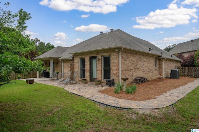 rear view of house featuring a patio area, cooling unit, brick siding, and a shingled roof