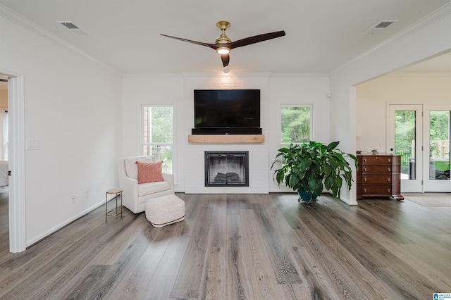sitting room with plenty of natural light, wood finished floors, a fireplace, and crown molding