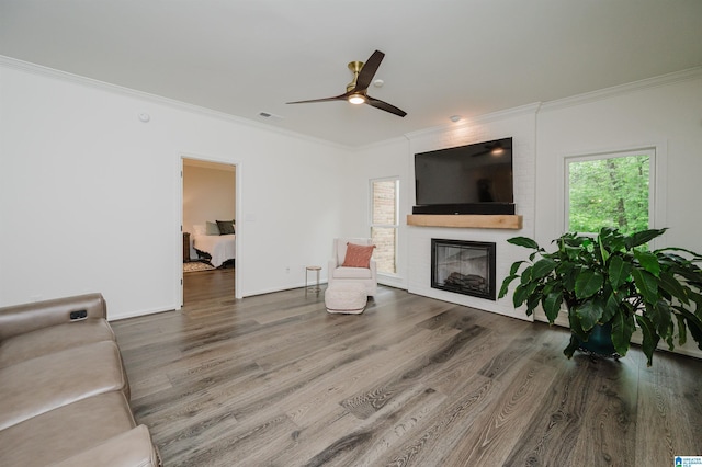 living room with ornamental molding, wood finished floors, a fireplace, a ceiling fan, and baseboards