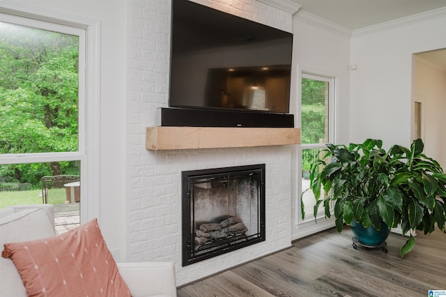 detailed view of a brick fireplace, wood finished floors, and crown molding