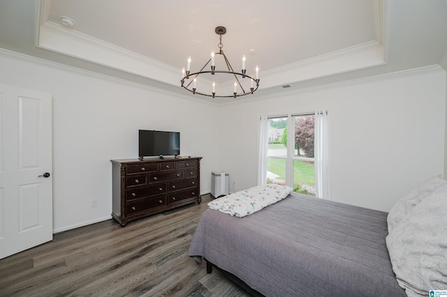 bedroom with a tray ceiling, a chandelier, crown molding, and wood finished floors