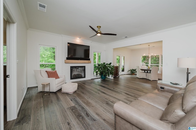 living room featuring crown molding, wood finished floors, a large fireplace, a chandelier, and a ceiling fan