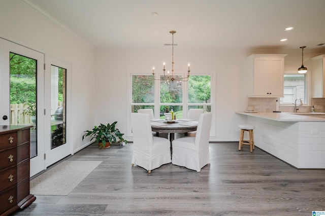 dining space with a chandelier, plenty of natural light, crown molding, wood finished floors, and recessed lighting