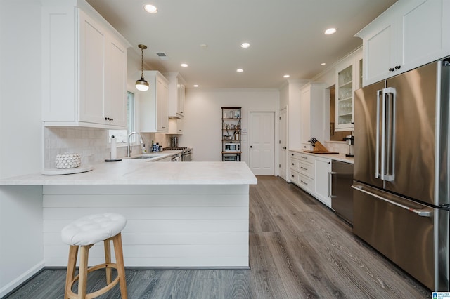 kitchen with stainless steel appliances, a sink, dark wood-type flooring, a peninsula, and glass insert cabinets