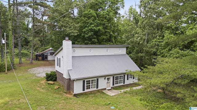 view of front of property featuring a chimney, a front lawn, and metal roof