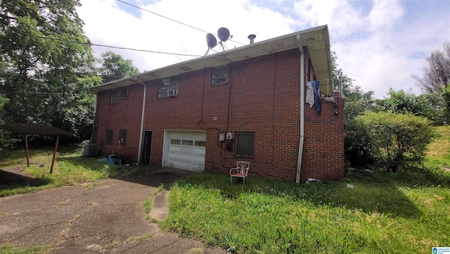view of side of property featuring concrete driveway, an attached garage, central AC, and brick siding