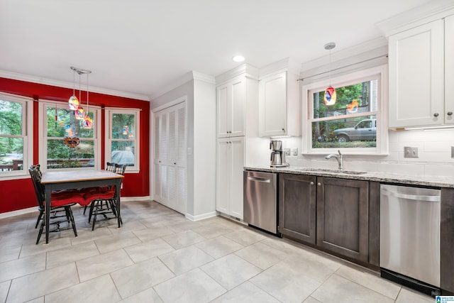 kitchen featuring stainless steel dishwasher, a sink, baseboards, and crown molding
