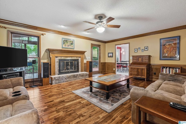 living area featuring crown molding, dark wood finished floors, ceiling fan, a fireplace, and a textured ceiling