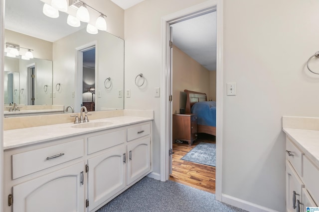 ensuite bathroom with vanity, baseboards, and wood finished floors