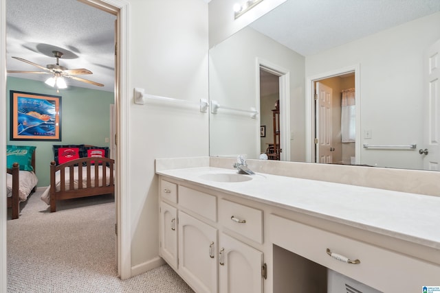 ensuite bathroom featuring a textured ceiling, a ceiling fan, vanity, and baseboards