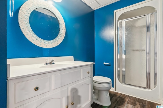 full bath featuring a stall shower, wood finished floors, toilet, and vanity