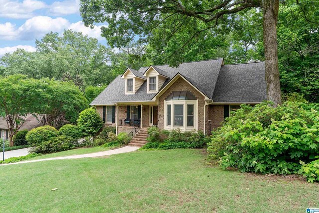 view of front of property featuring brick siding, a front yard, and roof with shingles