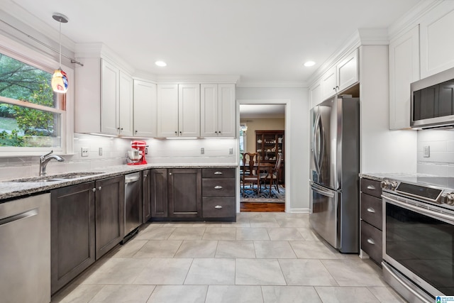 kitchen with appliances with stainless steel finishes, a sink, white cabinets, dark brown cabinetry, and tasteful backsplash