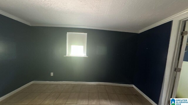 empty room with crown molding, a textured ceiling, and baseboards