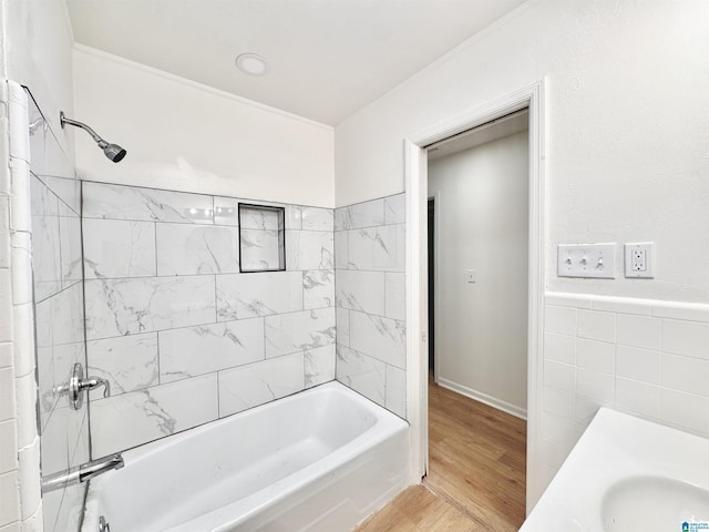 full bath with a sink,  shower combination, wood finished floors, and tile walls