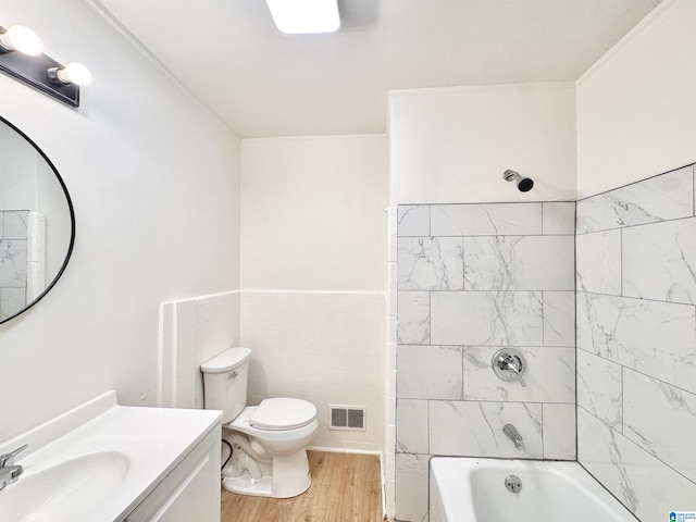 full bathroom featuring wood finished floors, toilet, vanity, tub / shower combination, and tile walls