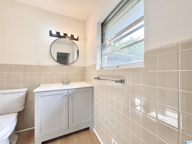 bathroom featuring tile walls, toilet, wainscoting, vanity, and wood finished floors