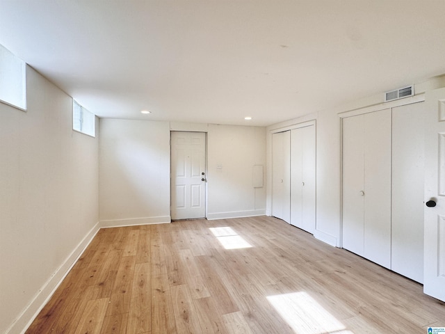 unfurnished bedroom featuring multiple closets, light wood-type flooring, baseboards, and recessed lighting