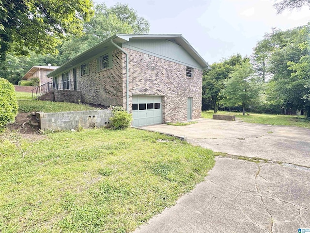 view of side of home featuring driveway, brick siding, a garage, and a lawn