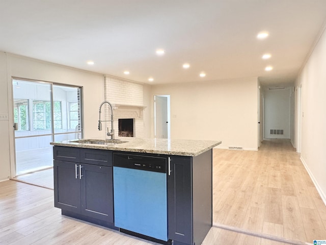 kitchen featuring dishwashing machine, a sink, open floor plan, an island with sink, and light wood-type flooring
