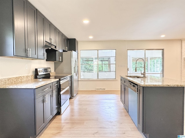 kitchen with stainless steel appliances, a sink, light wood finished floors, under cabinet range hood, and recessed lighting