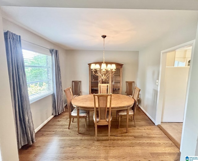 dining room with light wood-type flooring, a chandelier, and baseboards