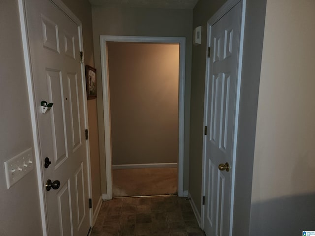 corridor with baseboards and dark flooring