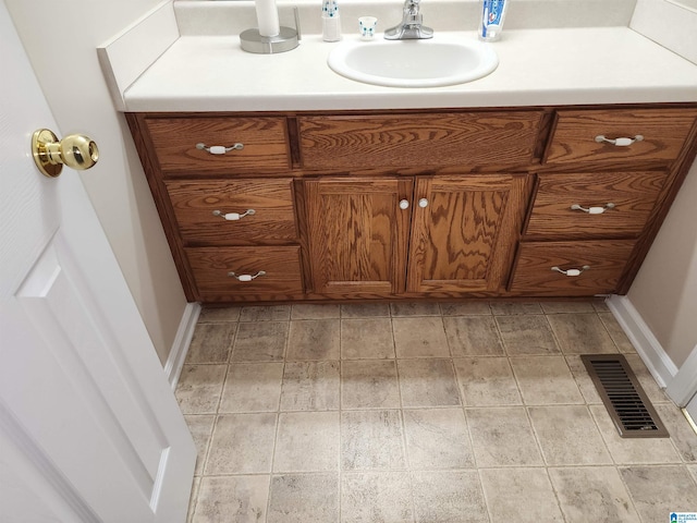 bathroom with vanity, baseboards, and stone finish flooring