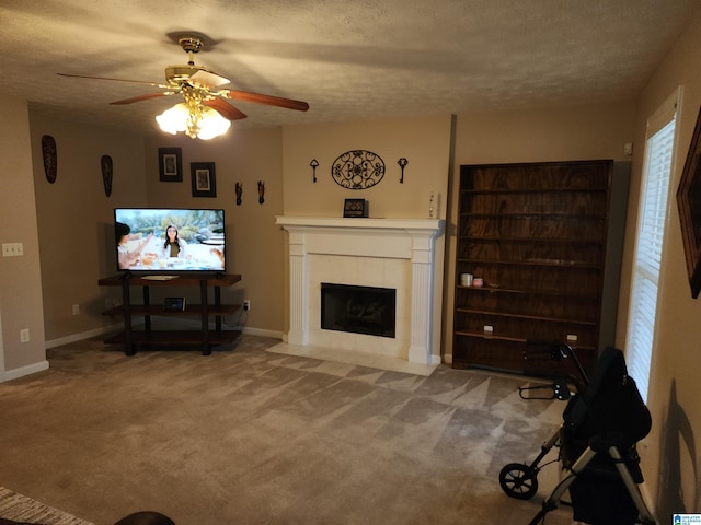 carpeted living area with a tile fireplace, a ceiling fan, a textured ceiling, and baseboards
