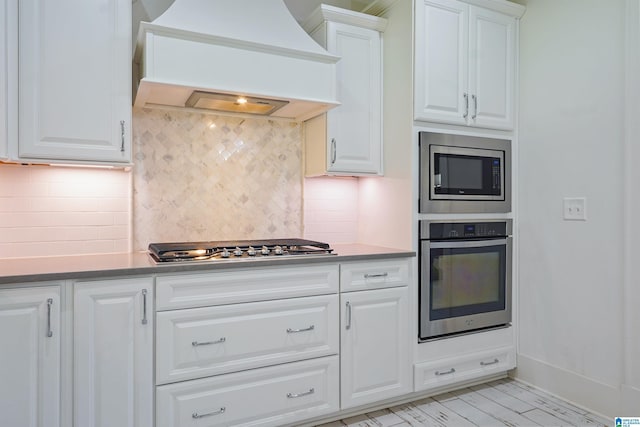 2126 Raines Run, Birmingham, AL 35242 - kitchen with stainless steel appliances, premium range hood, white cabinets, backsplash, and baseboards