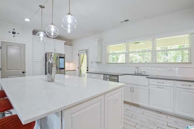 2126 Raines Run, Birmingham, AL 35242 - kitchen with appliances with stainless steel finishes, crown molding, a kitchen bar, white cabinetry, and a kitchen island