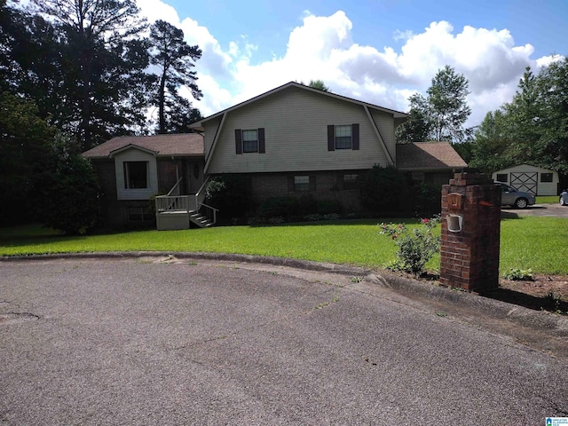 view of front facade with a gambrel roof, brick siding, and a front lawn