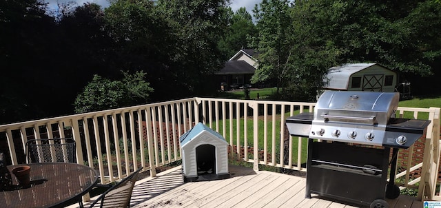 deck with grilling area, a storage unit, and an outbuilding