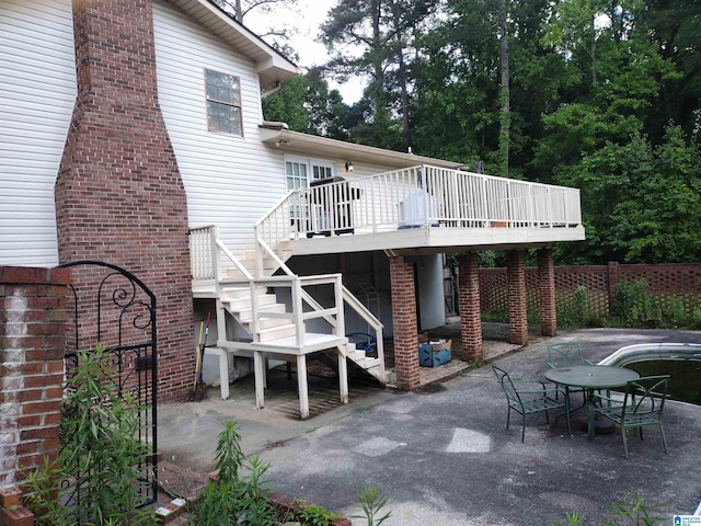 back of property with a wooden deck, a patio area, stairs, and fence