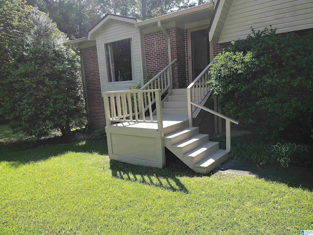 property entrance featuring a lawn and brick siding