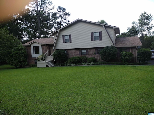 view of front of house featuring brick siding, a gambrel roof, a front yard, and roof with shingles