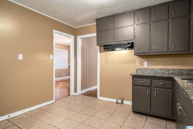 2444 4th St, Birmingham, AL 35215 - kitchen featuring under cabinet range hood, baseboards, light tile patterned floors, crown molding, and gray cabinets