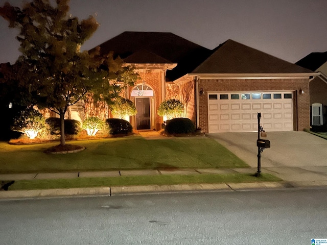 view of front facade with driveway, brick siding, an attached garage, and a yard