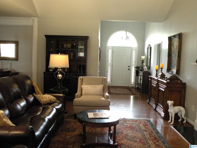 living area with dark wood finished floors, decorative columns, and baseboards