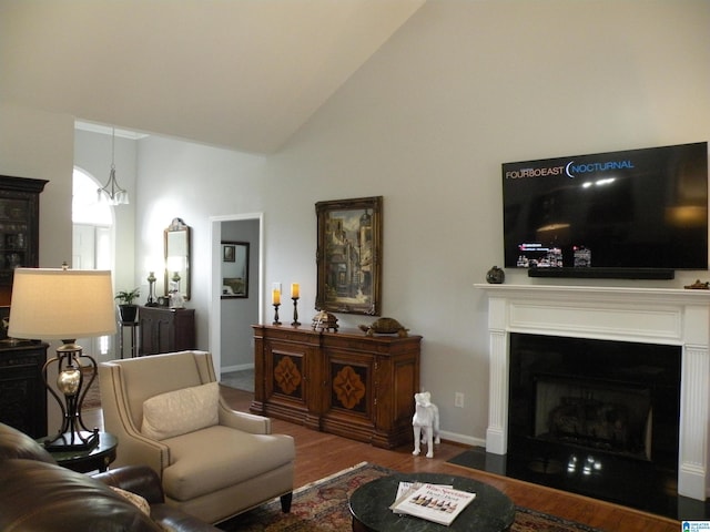 living area featuring wood finished floors, high vaulted ceiling, baseboards, and a fireplace with flush hearth