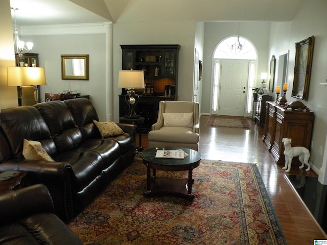 living room featuring wood finished floors, a chandelier, crown molding, and baseboards