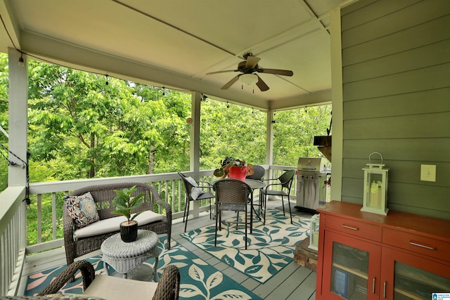 wooden terrace with grilling area, a ceiling fan, and outdoor lounge area