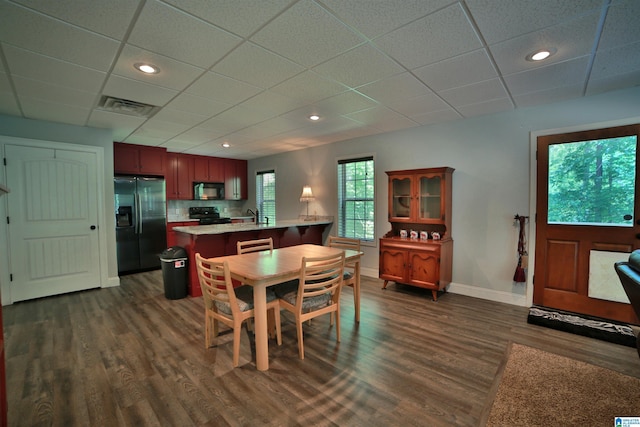dining area featuring dark wood-style flooring, baseboards, a drop ceiling, and recessed lighting