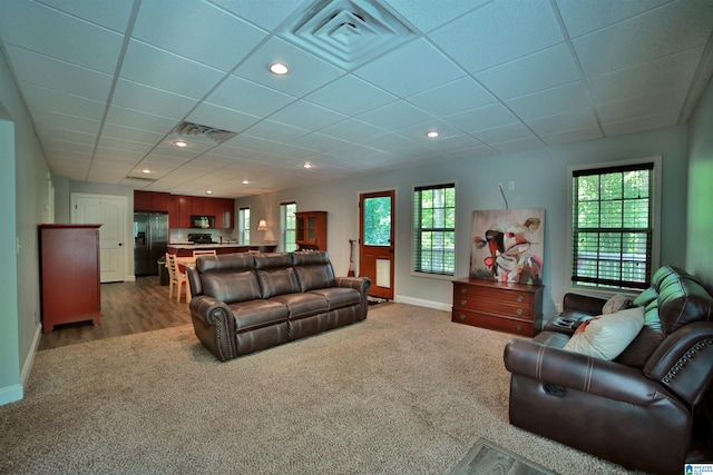carpeted living area with baseboards, a drop ceiling, and recessed lighting