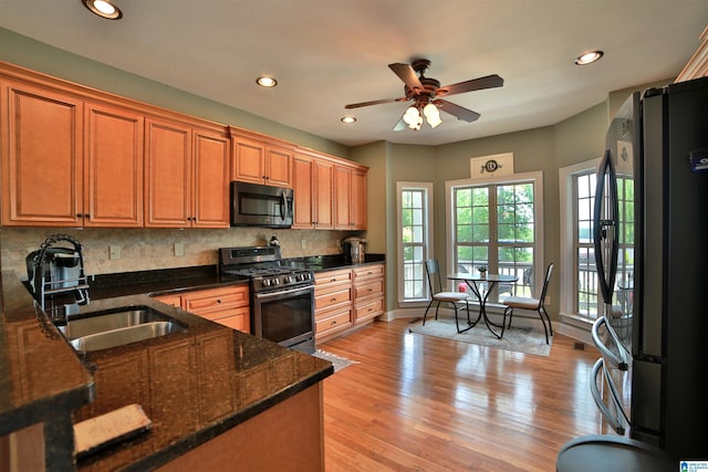 kitchen with stainless steel gas range, freestanding refrigerator, a sink, ceiling fan, and decorative backsplash