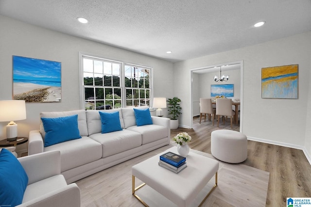 living room featuring a chandelier, a textured ceiling, wood finished floors, recessed lighting, and baseboards