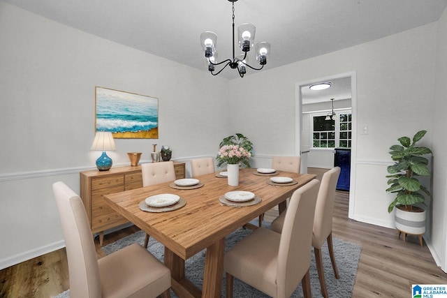 dining room featuring a chandelier, light wood finished floors, and baseboards