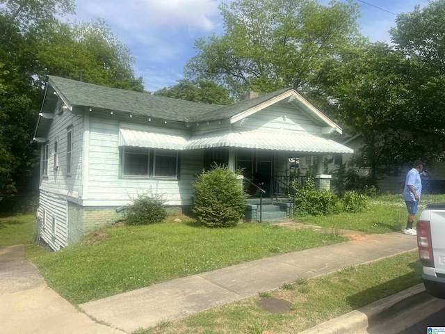 bungalow-style house featuring a porch, a front lawn, and a shingled roof