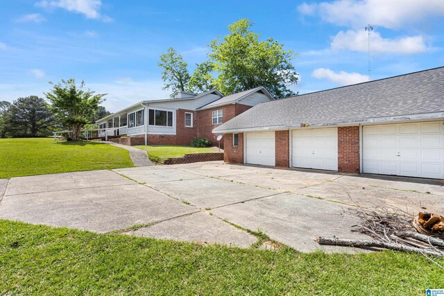 390 Chamblee Ln, Warrior, AL 35180 - view of front of house with brick siding, a front yard, driveway, and a sunroom